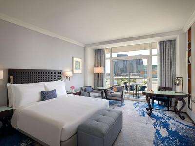 Modern eingerichtetes Hotelzimmer mit großem Bett, Sitzbereich und Blick auf die Stadt.