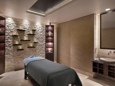 Eleganter Spa-Raum mit Massageliege, dekorativen Regalen und warmem Beleuchtungsdesign.