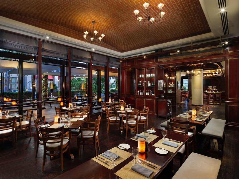 Elegantes Restaurant mit Holzmöbeln, gedeckten Tischen und großen Fenstern zum Außenbereich.