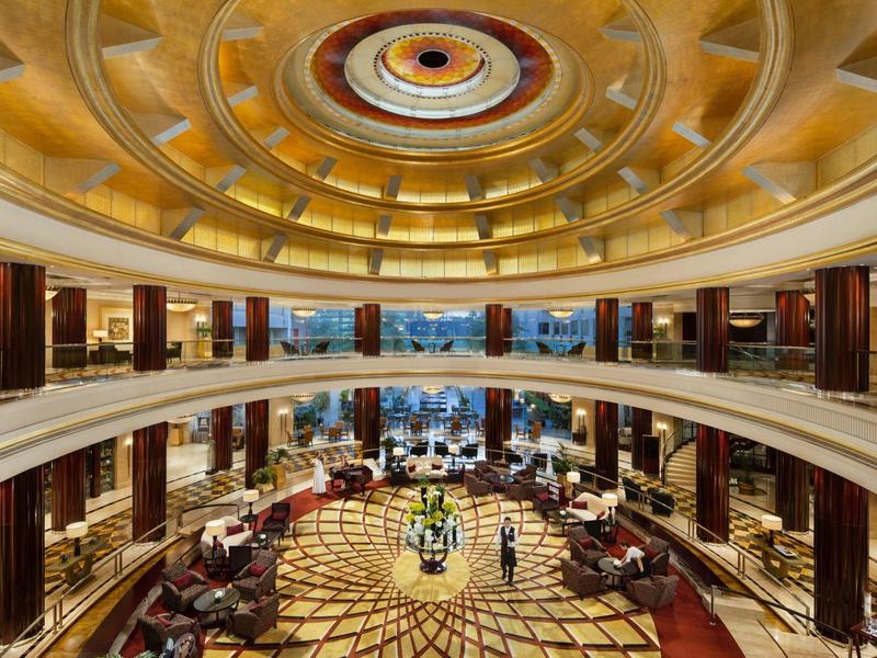 Weitläufige Hotellobby mit rundem goldenem Deckengewölbe und eleganter Sitzgruppe.