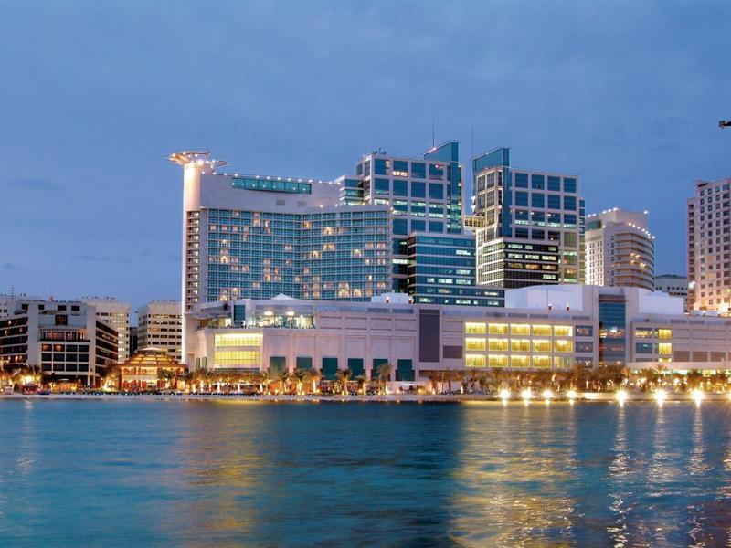 Kinder spielen in einem bunten Raum Tischfußball und Videospiele auf Bildschirmen an der Wand.