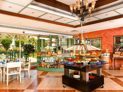 Ein heller, gemütlicher Frühstücksraum mit Tischen, Stühlen und einem Buffet in der Mitte.