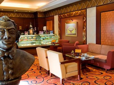 Gemütliches Café mit braunen Möbeln, Teppichboden und Bronze-Büste im Vordergrund.