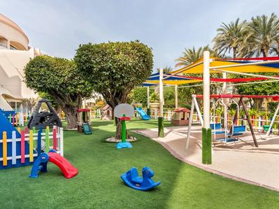 Bunter Kinderspielplatz mit Rutschen, Schaukeln und Klettergerüsten in einem Hotelgarten.