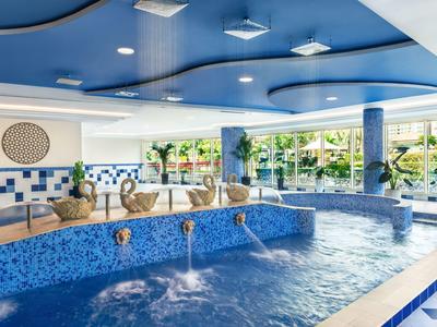 Innenraum mit blau gefliestem Whirlpool und Wasserfontänen in einem Hotel.