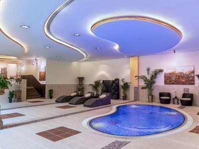 Moderner Wellnessbereich mit Whirlpool, Sonnenliegen und sanfter Beleuchtung im Hotel.