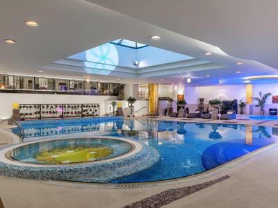 Moderner Innenpool mit Whirlpool in einem hellen Wellnessbereich eines Hotels.
