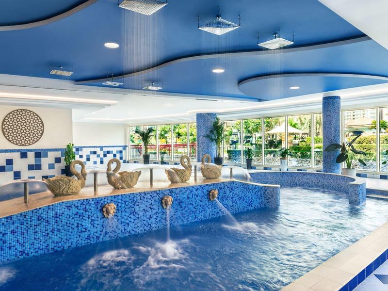 Innenpool mit blauer Fliesenverkleidung und Wasserspielen in einem Hotel.