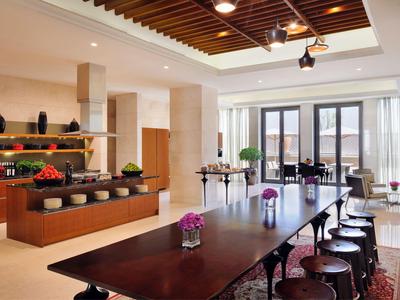 Moderner Speisesaal mit langem Holztisch, Stühlen und Buffetbereich in warmem Licht.