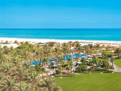 Blick auf eine tropische Hotelanlage mit Pool, Palmen und Strand am Ozean