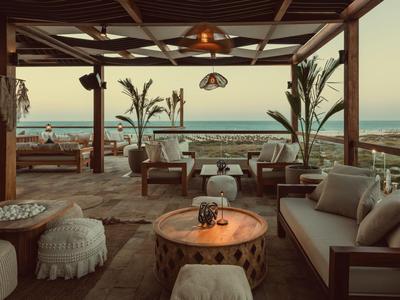 Gemütliche Lounge mit Sofas, Holztisch und Meerblick bei Sonnenuntergang.