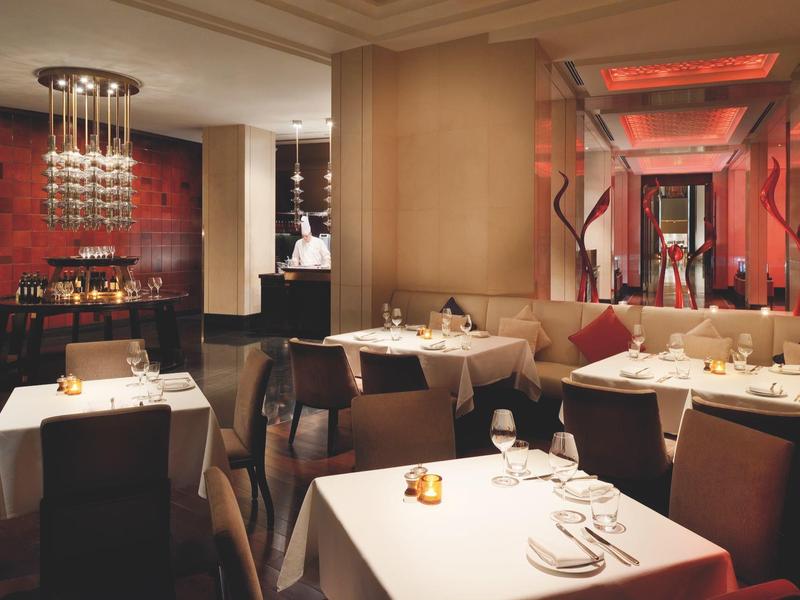 Elegantes Restaurant mit weißen Tischdecken, modernen Holzstühlen und warmem, gedämpftem Licht.