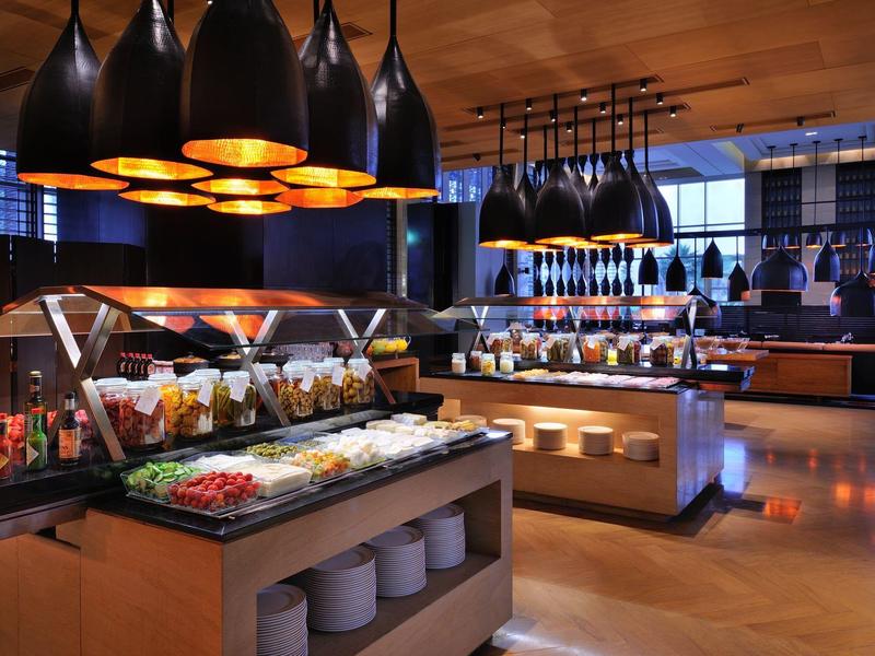 Modernes Buffet mit verschiedenen Speisen, warmen Holztönen und hellen Deckenlampen.