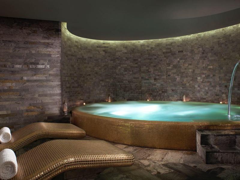 Moderne Spa mit rundem Whirlpool, braunen Wänden und zwei bequemen Liegen.