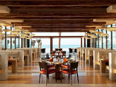 Restaurant moderne avec plafond en poutres de bois et vue sur la mer.