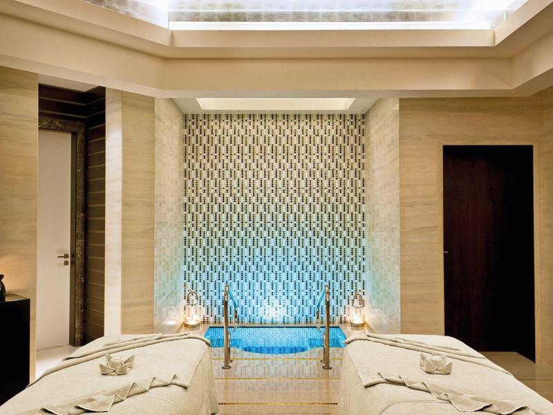 Luxuriöses Spa mit zwei Massageliegen und beleuchteter Wanddekoration.