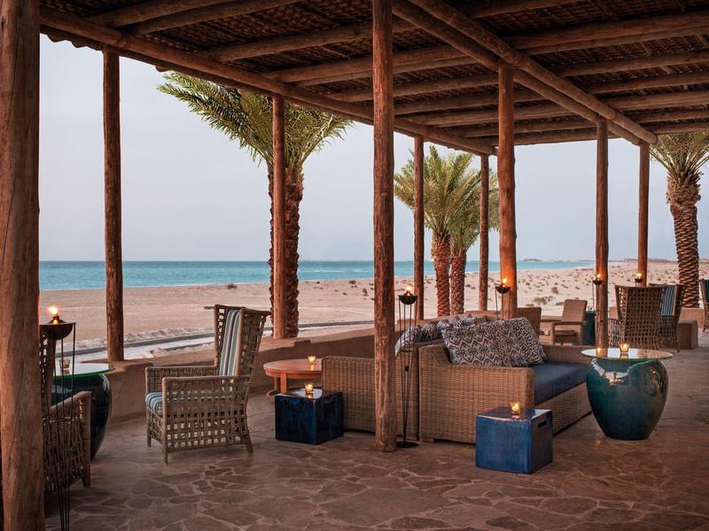 Gemütlicher Lounge-Bereich mit Korbmöbeln und Blick auf den Strand und das Meer.