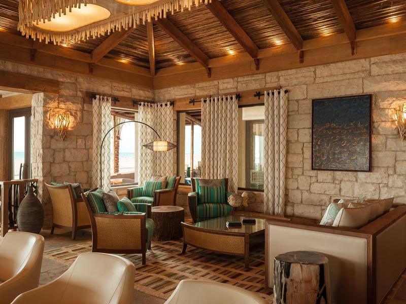 Gemütlicher Hotel-Lounge mit Holzbalkendecke, Steinfwand und eleganten Möbeln.