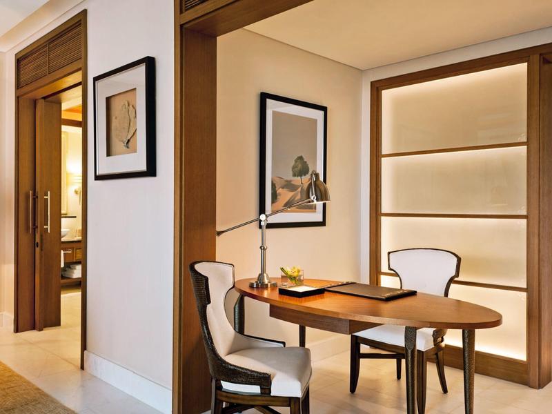 Moderner Arbeitsplatz in einem Hotelzimmer mit Schreibtisch, zwei Stühlen und Kunst an der Wand.