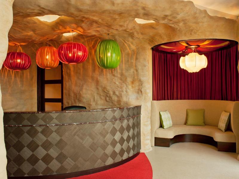 Gemütliche Hotellobby mit farbigen Lampen und weichen Sitzgelegenheiten in einer Höhlenwand.