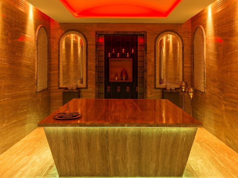 Luxuriöser Spa-Raum mit beleuchtetem Massagebett und warmer, roter Beleuchtung.