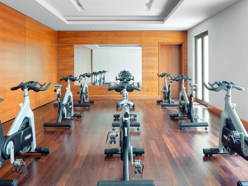 Moderner Fitnessraum mit mehreren Spinning-Bikes und Holzboden.