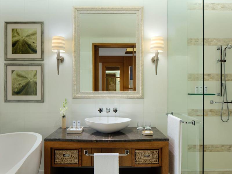 Modernes Badezimmer mit Waschbecken, Holzunterschrank, Badewanne und Dusche.