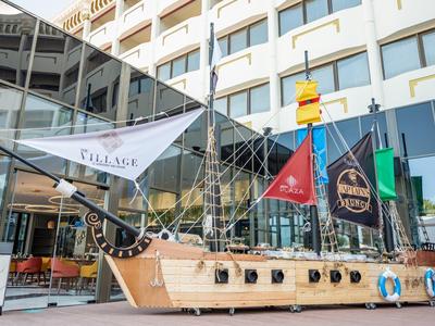 Ein großes hölzernes Piratenschiff steht vor einem modernen Hotelgebäude mit Glasfassade.