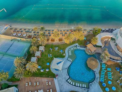 Luftaufnahme eines Resorts mit Pool, Tennisplatz und direktem Zugang zum Meer