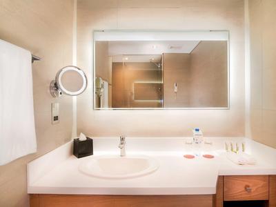 Moderner Hotelbadezimmer-Spiegel mit LED-Beleuchtung, Waschbecken und Handtuchhalter an der Wand.