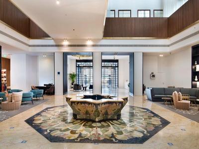 Moderne Hotellobby mit eleganten Sitzbereichen, Teppich und zentralem Blumenarrangement.