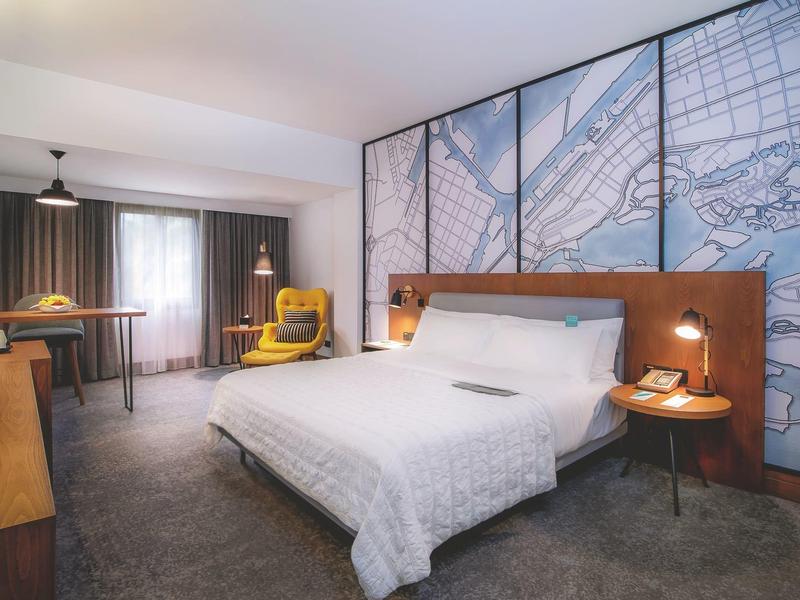 Modernes Hotelzimmer mit Doppelbett, Schreibtisch und großem Stadtplan an der Wand