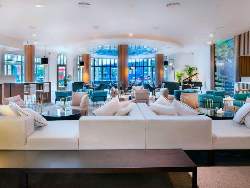 Moderne Hotellobby mit komfortablen weißen Sofas und großen Fenstern mit Meeresblick.