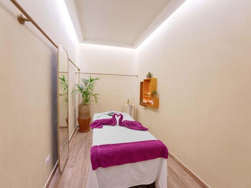 Schlichte Wellness-Massagekammer mit Massagebett, Pflanzen und sanfter Beleuchtung