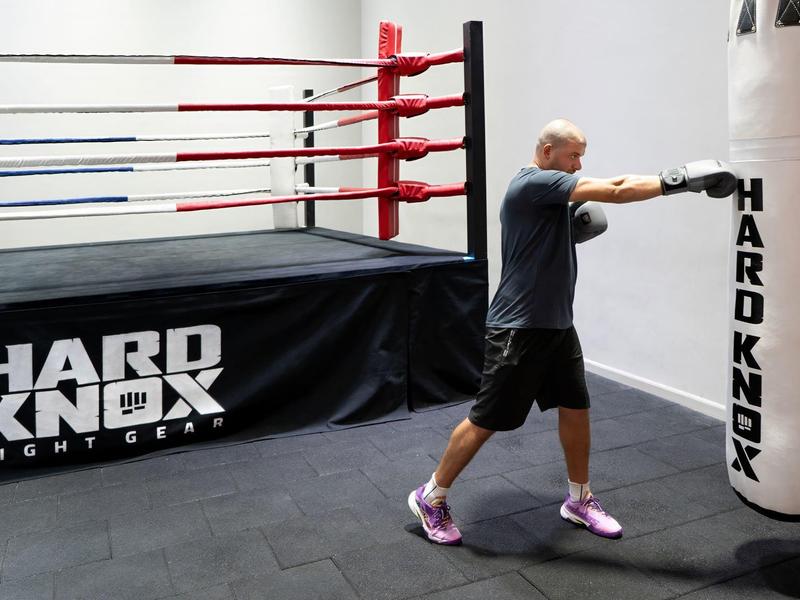 Ein Mann trainiert Boxen mit einem weißen Boxsack in einem Fitnessstudio.