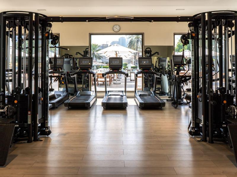 Moderner Fitnessraum mit Laufbändern, Kraftmaschinen und großen Fenstern mit Bergblick.