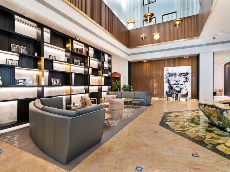 Modern eingerichteter Hotel-Loungebereich mit Sesseln und Bücherregal an der Wand.