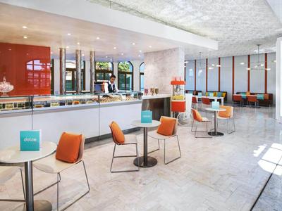 Helles Café mit modernen orangefarbenen Stühlen, weißen Tischen und großem Fenster für Tageslicht.