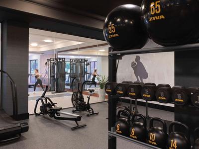 Moderner Fitnessraum mit Laufbändern, Rudergeräten und Hanteln in einem Hotel.