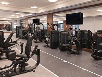 Großer Fitnessraum mit modernen Trainingsgeräten und TV-Bildschirm in einem Hotel.