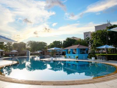 Runder Hotelpool mit Sitzbereichen und Sonnenschirmen bei Sonnenuntergang.