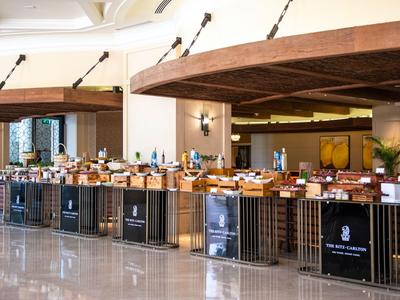 Ein moderner Buffetbereich in einem Hotel mit vielfältigen Speisen auf langen Tischen und hellem Fußboden.