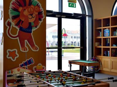 Innenraum eines Spielzimmers mit Tischkicker, Regal und bunter Löwenwanddekoration im Hotel.