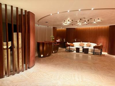 Moderner Hotel-Loungebereich mit warmem Holzdesign, bequemen Sitzgelegenheiten und elegantem Beleuchtungskonzept.