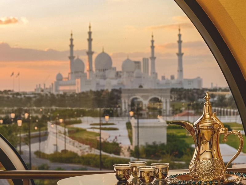Vista sulla moschea Sheikh Zayed al tramonto attraverso una finestra con una caffettiera tradizionale.