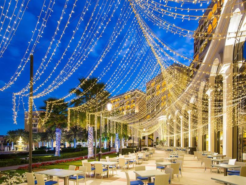 Area esterna di un hotel con tavoli e luci decorative di sera.