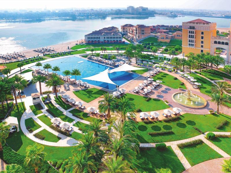 Grande resort con piscina e spiaggia sulla costa, circondato da prati verdi e lettini.