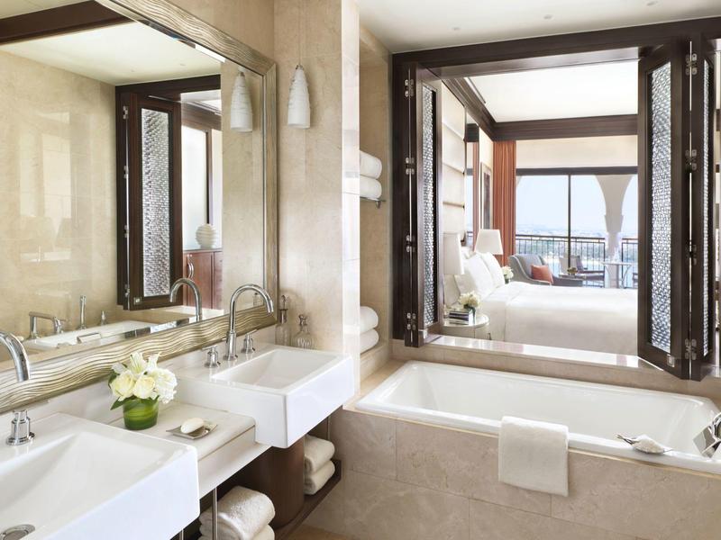 Bagno di lusso con lavandino e vasca da bagno, vista su un soggiorno luminoso.