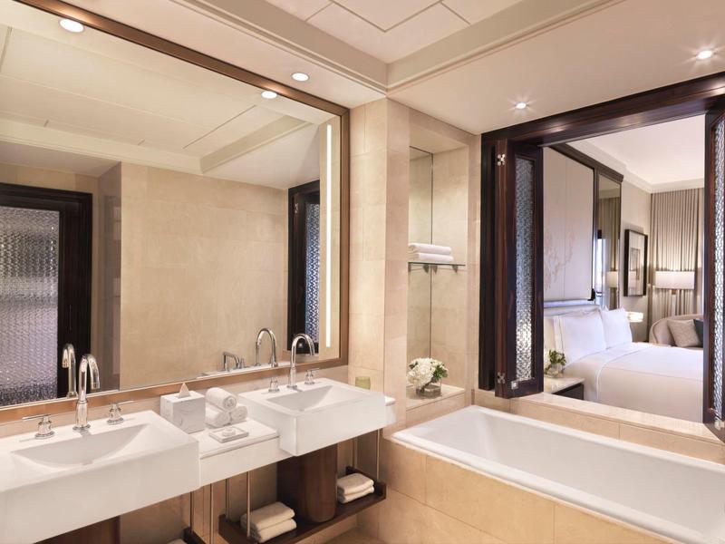 Bagno moderno con ampia vasca da bagno, doppi lavandini e vista sulla camera.