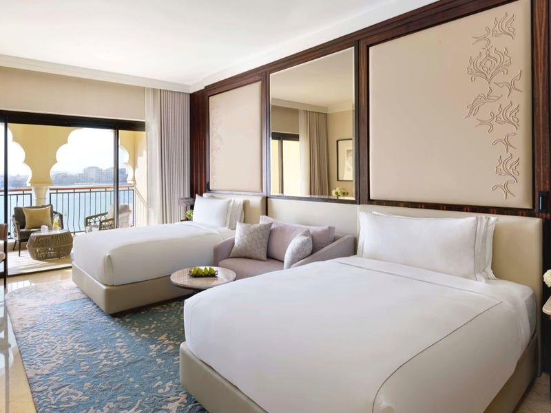 Elegante camera d'hotel con letto, divano, tappeto e balcone con vista mare.